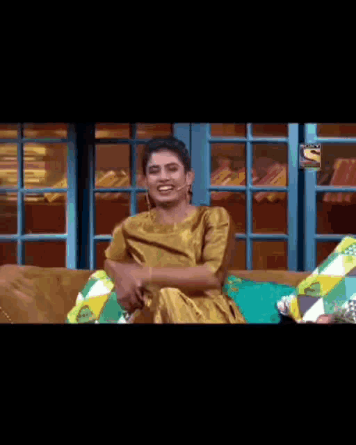 a woman in a yellow dress is sitting on a couch and covering her mouth
