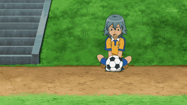 a boy sitting on the ground with a soccer ball