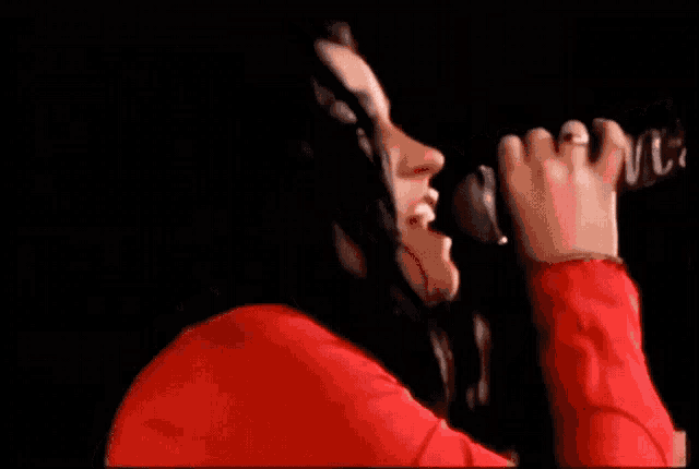 a woman in a red shirt sings into a microphone that says marie
