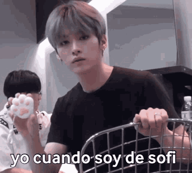 a young man in a black shirt is holding a cat paw and says yo cuando soy de sofi