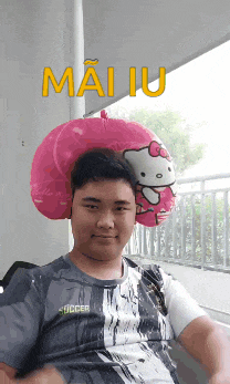 a man with a hello kitty pillow on his head and the word mai iu above him