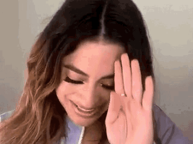 a woman is covering her face with her hand while smiling .