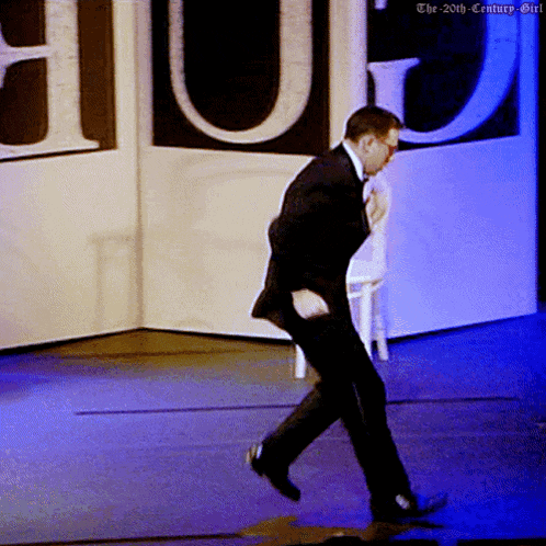 a man in a suit is dancing on a stage with the 20th century girl written on the bottom