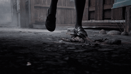 a person 's feet are shown in a dark scene with a fence in the background