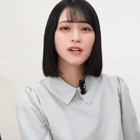 a young woman with short black hair is wearing a white shirt and a microphone on her neck .
