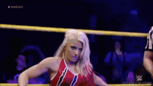 a female wrestler is standing in a wrestling ring holding a cup .