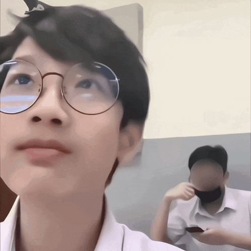 a young boy wearing glasses looks up at something