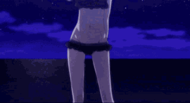 a woman in a black bikini is standing on a beach at night .