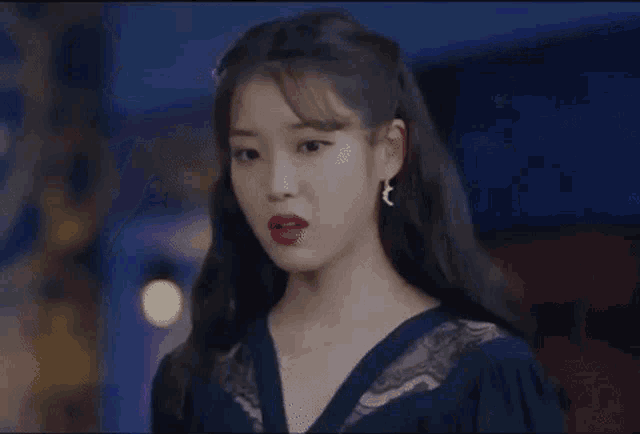 a woman wearing a blue dress and red lipstick is standing in a room .