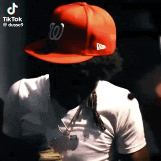 a man wearing a red hat and a white shirt with a necklace .
