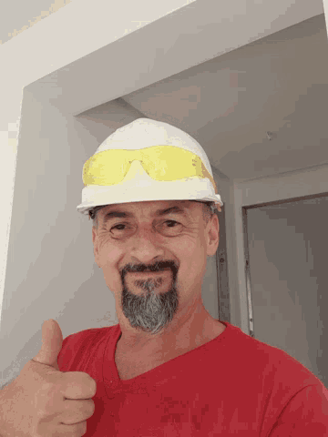 a man with a beard wearing a hard hat and goggles giving a thumbs up
