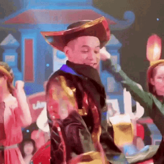 a man in a cowboy hat is dancing in front of a crowd while holding a beer .