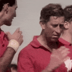 a man in a red shirt is standing next to another man in a red shirt .