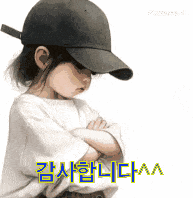 a little girl wearing a baseball cap has her arms crossed in front of a white background