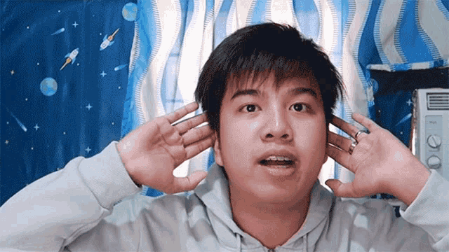 a man covering his ears with his hands in front of a window