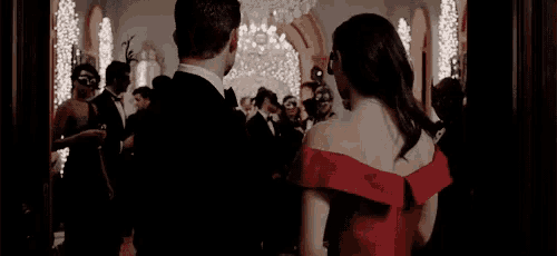 a man in a tuxedo is standing next to a woman in a red dress .