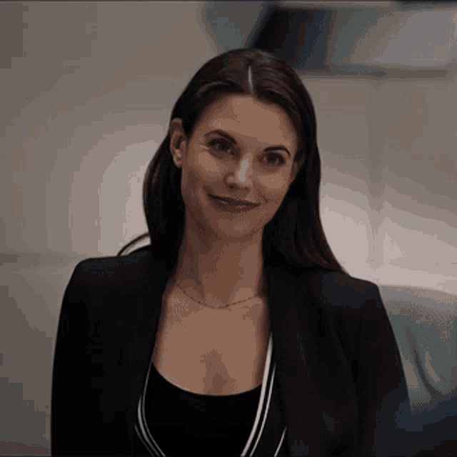 a woman wearing a black jacket and a black top is smiling