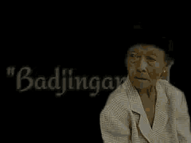 an elderly woman is sitting in front of a black background with the words badjingar written in white letters .