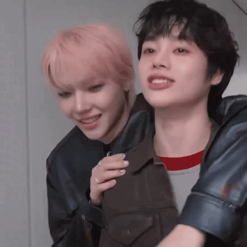 a man with pink hair is holding another man 's jacket