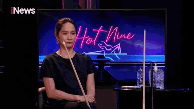 a woman is sitting in front of a screen that says hot news