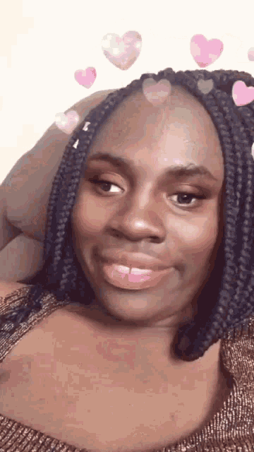 a woman with braids is sitting on a couch with hearts in her hair .