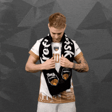 a man wearing a shirt with the number 10 on it holds a black scarf around his neck