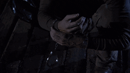 a man is sitting on the side of a boat with his hands in his pockets
