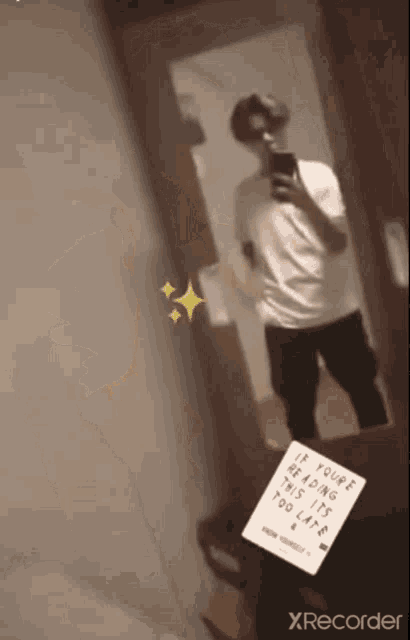 a man taking a picture of himself in a mirror with a sign that says if you 're reading this its too late