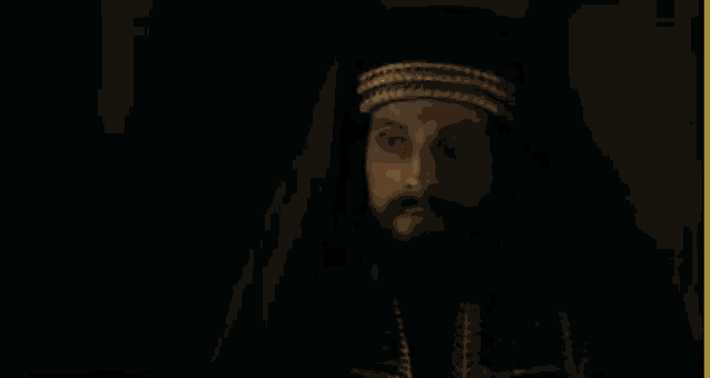 a man with a beard is wearing a black robe and hat