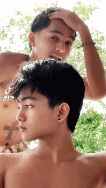 a man without a shirt is standing next to another man without a shirt .