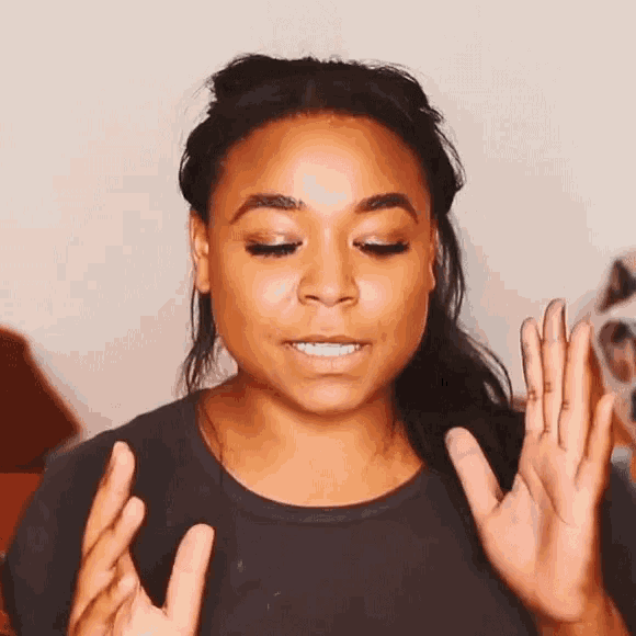 a woman is making a funny face while holding her hands up in the air .