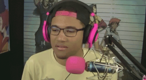 a man wearing headphones and a pink headband stands in front of a pink microphone