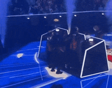 a group of people are dancing on a stage with blue smoke coming out of them