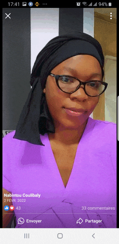 a woman wearing glasses and a head scarf is displayed on a cell phone screen
