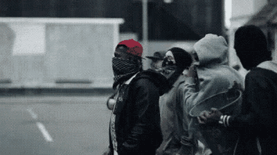 a group of people are standing next to each other on a street wearing face masks .