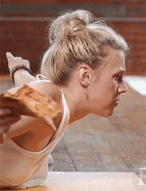 a woman laying on a yoga mat with a slice of pizza on her face