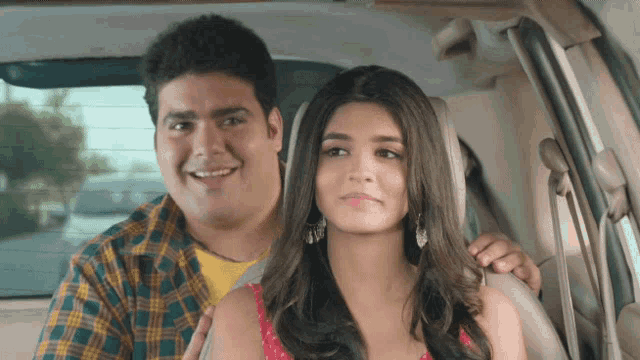 a man and a woman are sitting in a car and the man is smiling