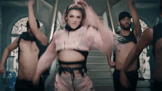 a woman in a pink top is dancing with a group of men