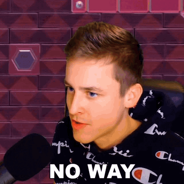 a man wearing a champion shirt says " no way " in front of a microphone