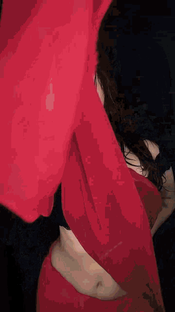 a woman in a red top is dancing with a red cloth