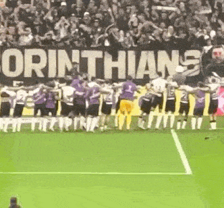 a group of soccer players are standing on a soccer field in front of a sign that says corinthians .