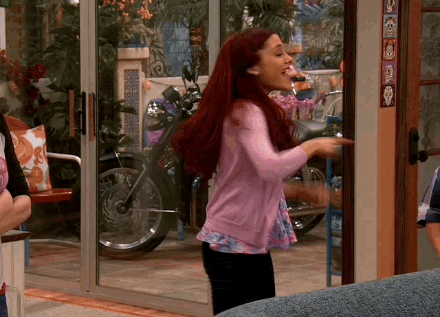 a woman in a pink sweater stands in front of a glass door
