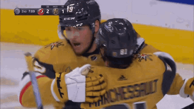 two hockey players are hugging each other and one has a jersey that says manchester