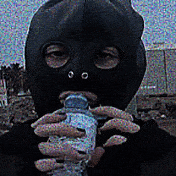 a person wearing a black mask is holding a bottle in their hands