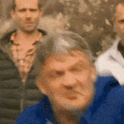 a blurry picture of a man in a blue jacket looking at the camera