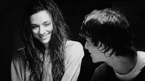 a black and white photo of a boy and a girl looking at each other .