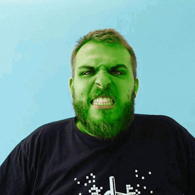 a man with green paint on his face is wearing a black shirt with a pixelated arrow on the front