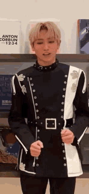 a man in a black and white uniform is standing in front of a bookshelf with books on it .