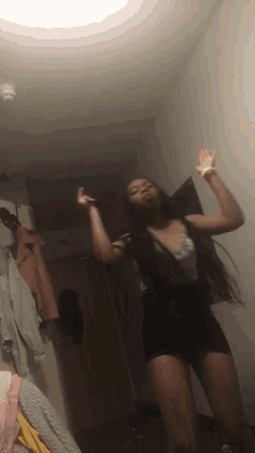 a woman is dancing in a dark room with her arms in the air