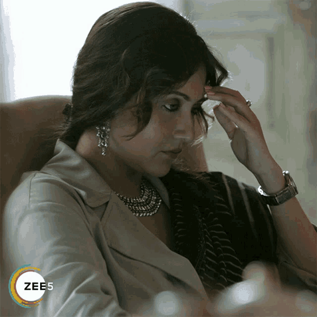 a woman sitting in a chair with the word zees on the bottom right